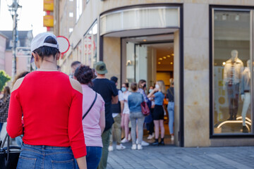 Selected focus view, Group of European women queue and wait for shopping on sidewalk outside store...
