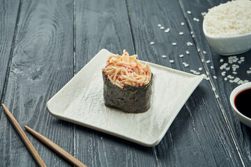 Classic japanese sushi rolls - gunkan with crab and spicy white sauce on a white ceramic plate on a black wooden background. Close up