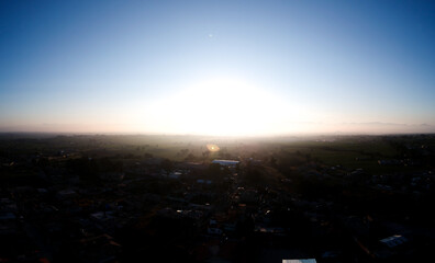 Fotografía aérea del amanecer en una zona semirural con la ciudad de fondo