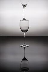 Glasses for wine stand on top of each other on a black and white background.