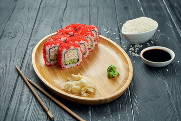 Classic japanese sushi rolls - california roll with tobiko caviar, cucumber and crab on a bamboo plate on a black wooden background