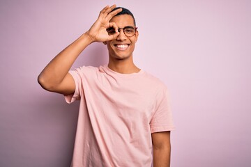 Handsome african american man wearing casual t-shirt and glasses over pink background doing ok gesture with hand smiling, eye looking through fingers with happy face.