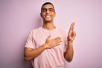 Handsome african american man wearing casual t-shirt and glasses over pink background smiling...