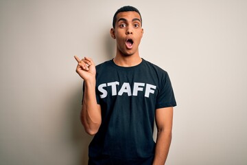 Young handsome african american worker man wearing staff uniform over white background Surprised pointing with finger to the side, open mouth amazed expression.