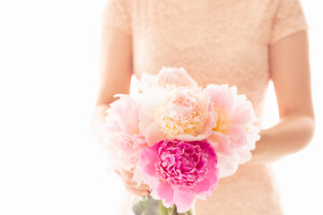 Obraz na płótnie Canvas Pink peonies in woman's hands. Elegant bunch of beautiful flowers, soft white background, shallow dof, copy space. Love, wedding, Valentine Day, romantic concept