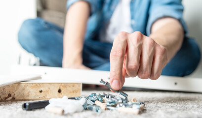 Fototapeta na wymiar Hand grabbing screw. Man assembling new furniture for home concept