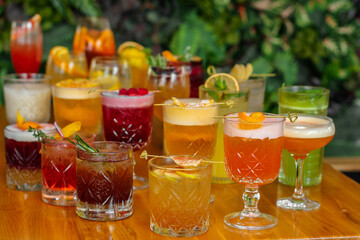 Set of alcoholic multicolor cocktails with fruits on the wooden table.