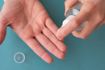 Hands using spray bottle with antiseptic liquid as concept of health care, self-hygiene and prevention of coronavirus spreading. Top view photo