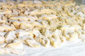 kitchen table. Sprinkled with flour. On it are dough products. Brushwood. Close-up