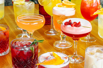 Set of alcoholic multicolor cocktails with fruits on the wooden table.