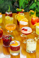 Set of alcoholic multicolor cocktails with fruits on the wooden table.