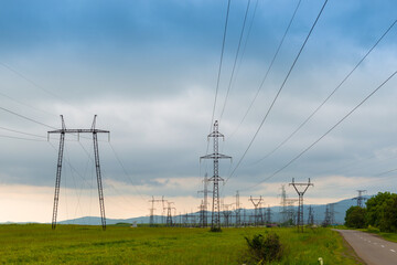 Power lines in a green field and dark blue clouds