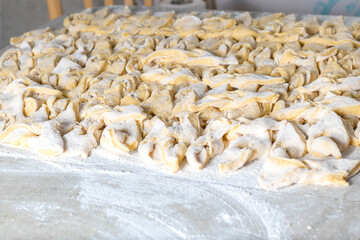 kitchen table. Sprinkled with flour. On it are dough products. Brushwood. Close-up