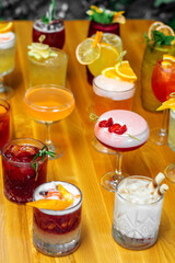 Set of alcoholic multicolor cocktails with fruits on the wooden table.