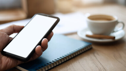 Close up of hand holding mobile phone and use 5g teachnology working or shopping online with notebook and coffee drink