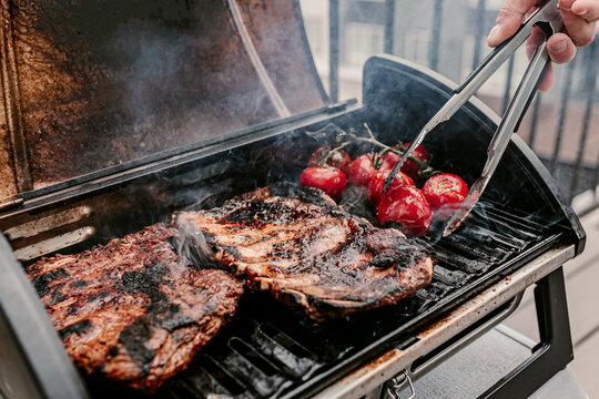 American Style Barbeque Dinner. Gas Grill. Making Smoked Food On Balcony. Grilled Pork Ribs. Red Tomatoes. Charcoal Bbq. Fourth Of July. Independence Day Lunch. Family Holiday Meal. Backyard Party