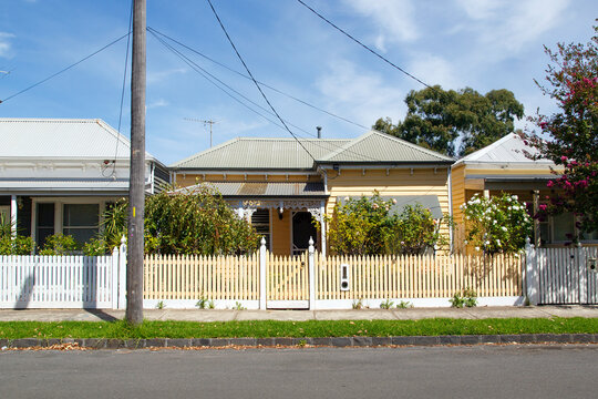  Traditionally built row of bungalow cottages in the 20th century Australian style with painted picket fences. Some of the houses require painting.