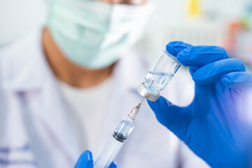 Fototapeta premium Doctor in blue glove filling syringe with vaccine