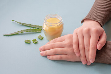 Young female hands are holding translucent glass jar with cream made of wax and aloe essence.Revitalizing soft cream as organic moisturizer.