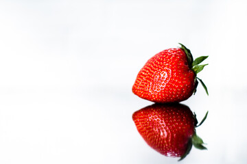 red strawberries with a reflection on a white background. place to insert text