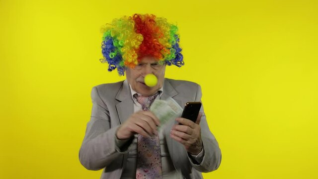 Senior clown businessman entrepreneur loses money while working on phone online