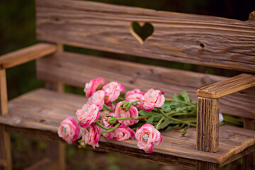 Fototapeta na wymiar bouquet of ranunculus flowers on an old wooden bench on summer nature