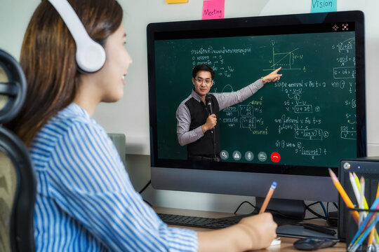 Rear View Of Asian Student Learning With Teacher Over The Physics Formular In Thai Laguage On Black Board Via Video Call Conference