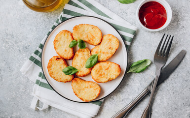 Hash brown or potato pancakes on plate with catsup on light gray background