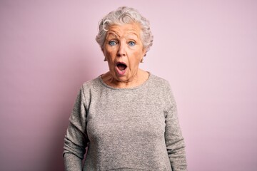 Senior beautiful woman wearing casual t-shirt standing over isolated pink background afraid and...