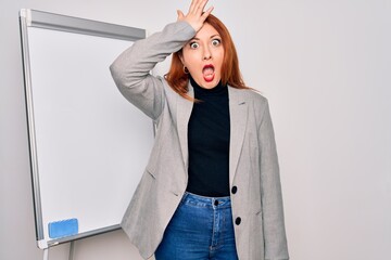 Young beautiful redhead businesswoman doing business presentation using magnetic board surprised...