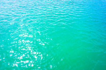Fototapeta na wymiar Texture of a turquoise water surface with small waves in the sun light as a background