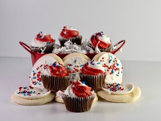 Chocolate mini cupcakes with red and white frosting and star sprinkles along with sugar cookies with white frosting and red, white and blue sprinkles for 4th of July, Memorial Day, Veterans Day.