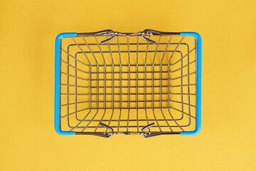 Top view of supermarket shopping basket on yellow background. Black friday sale concept. Copy space.