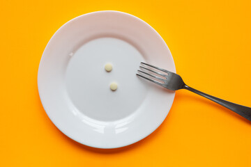 On the plate are two tablets and a fork, orange background