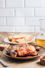 Chicken drumsticks on brown plate and french fries on white plate on wooden table.