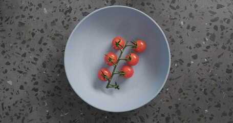 cherry tomatoes in blue ceramic bowl on concrete background