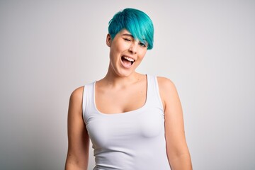 Young beautiful woman with blue fashion hair wearing casual t-shirt over white background winking looking at the camera with sexy expression, cheerful and happy face.