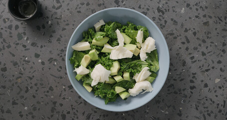 Top view salad put mozzarella over avocado and kale leaves in blue ceramic bowl on concrete background