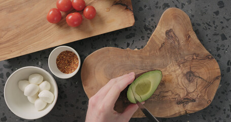 Top view man hands slice half of ripe avocado on concrete countertop