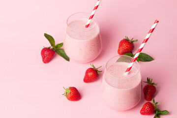 A glass of fresh strawberry smoothie on a pink background. Summer drink shake, milkshake and...