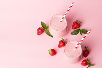 A glass of fresh strawberry smoothie on a pink background. Summer drink shake, milkshake and refreshment organic concept.