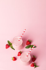 A glass of fresh strawberry smoothie on a pink background. Summer drink shake, milkshake and refreshment organic concept.