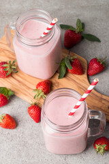 A glass of fresh strawberry smoothie on a grey background. Summer drink shake, milkshake and refreshment organic concept.