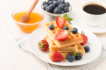 Photo of fresh homemade food made of Belgian waffles with honey, chocolate, strawberry, blueberry. Healthy dessert breakfast concept. 