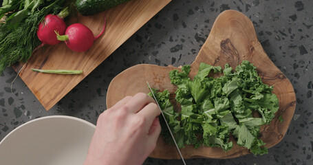 Top view man hands cut kale leaves on concrete countertop