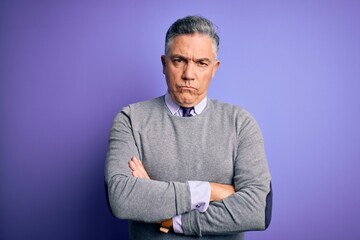 Middle age handsome grey-haired man wearing elegant sweater over purple background skeptic and...