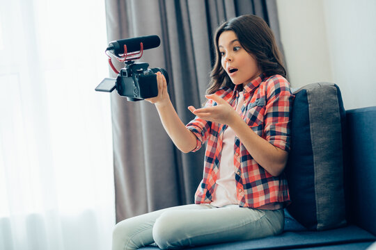 Astonished girl recording herself on modern camera