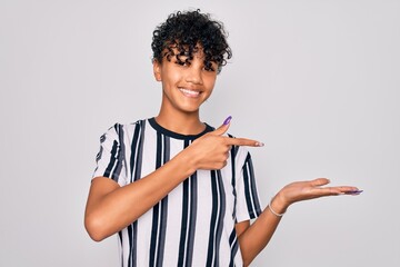 Beautiful african american afro woman wearing casual striped t-shirt over white background amazed and smiling to the camera while presenting with hand and pointing with finger.