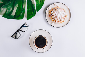 Flat lay of Belgian waffles with marshmallows and coffee on white background. Top view. Minimal concept