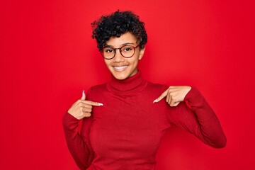 Young beautiful african american afro woman wearing turtleneck sweater and glasses looking confident with smile on face, pointing oneself with fingers proud and happy.